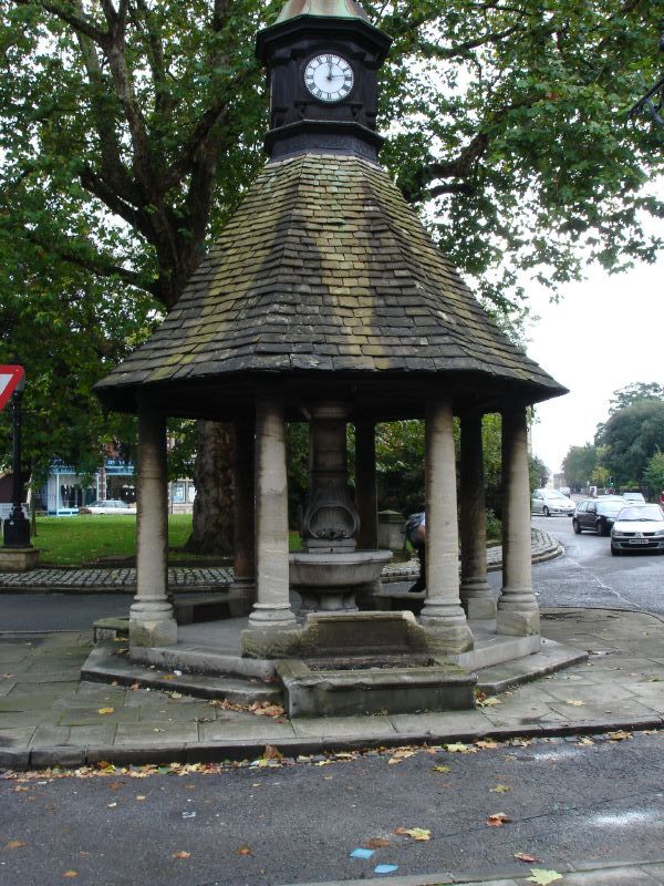 This is probably an old fountain or what, standing in the middle of a street, next to a roundabout.